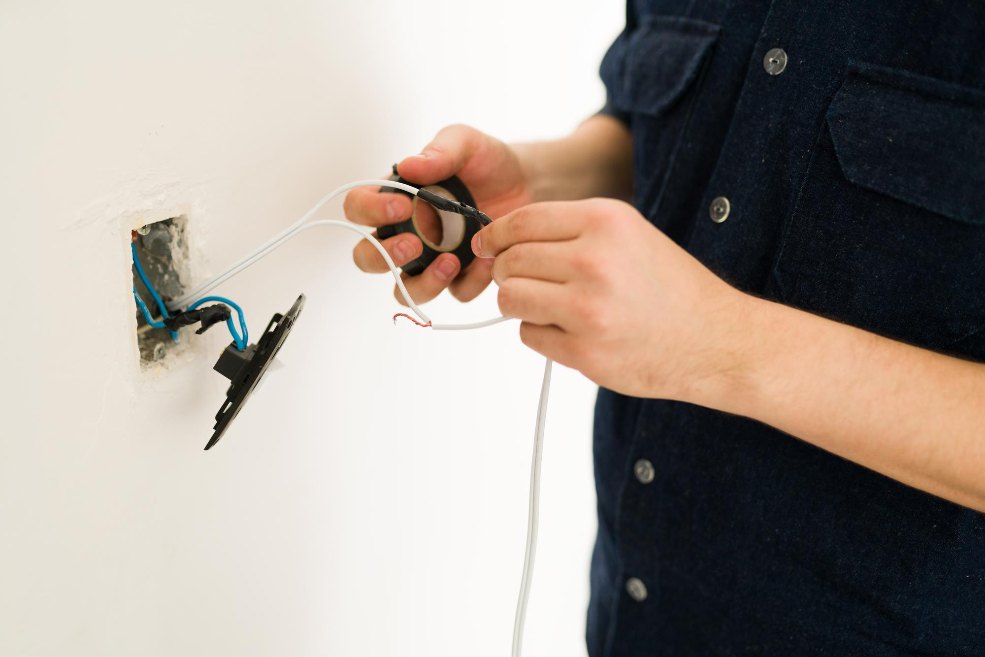 handyman working on electrical wiring during a wall switch repair